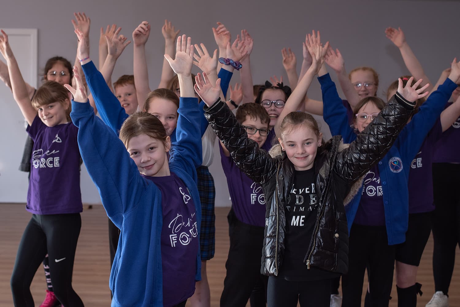 Young people in a PPP session — arms raised, Dance Force and programme colours